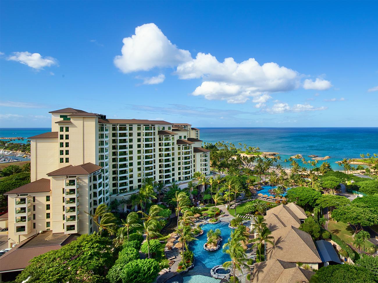 Aerial of exterior of Marriott's Ko Olina Beach Club resort timeshare showing pool complex and ocean at a distance