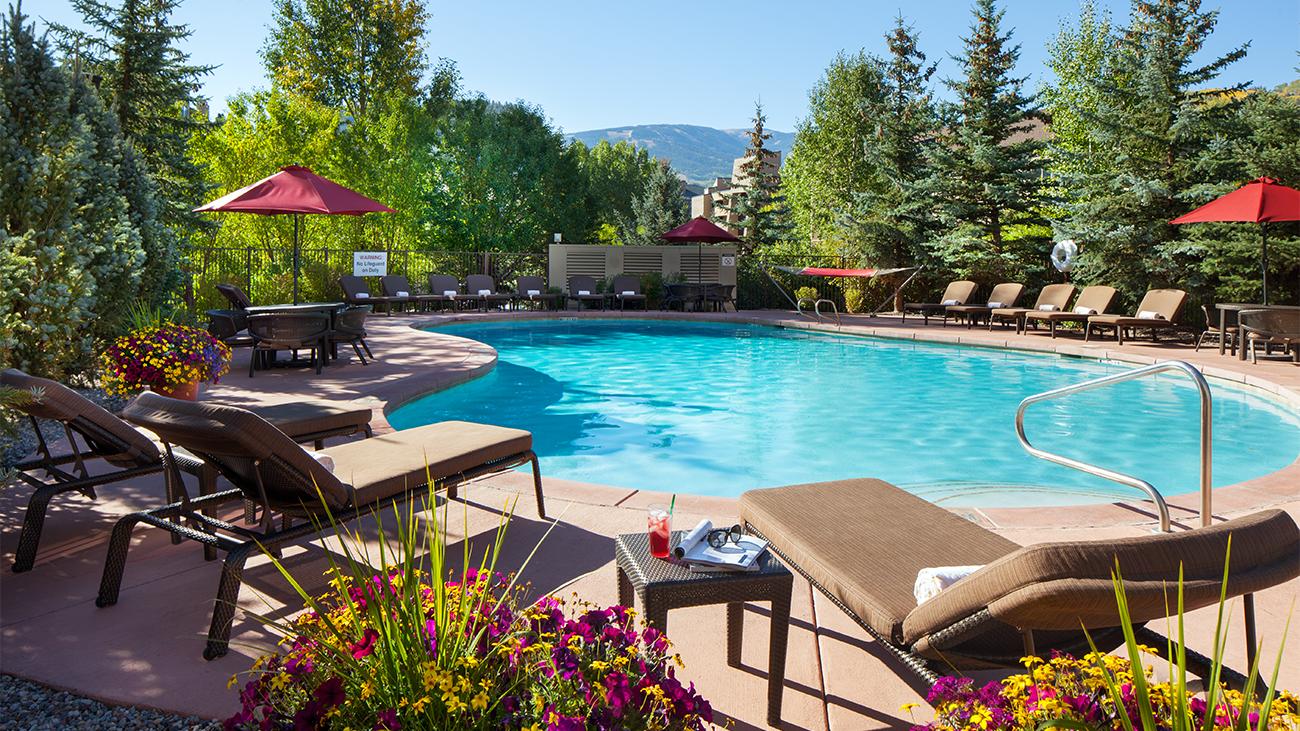 Pool area at a Colorado resort surrounded by pine trees with mountains in the background