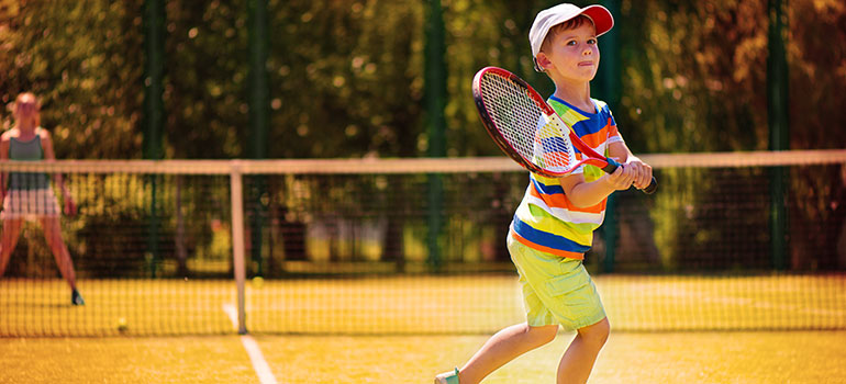 Young boy with a determined expression running on a tennis court at the Sheraton Vistana Resort timeshare, Orlando