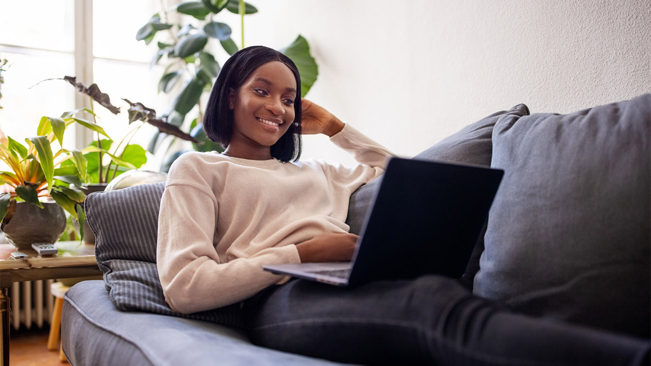 Woman sitting on a couch looking at her laptop.