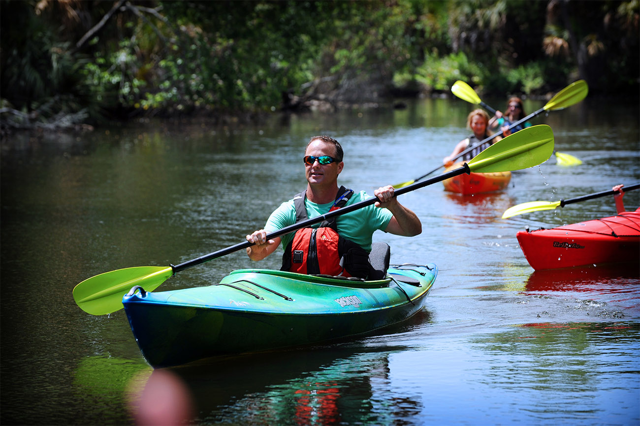 Kayakers float down the Homosassa River under a clear sky.