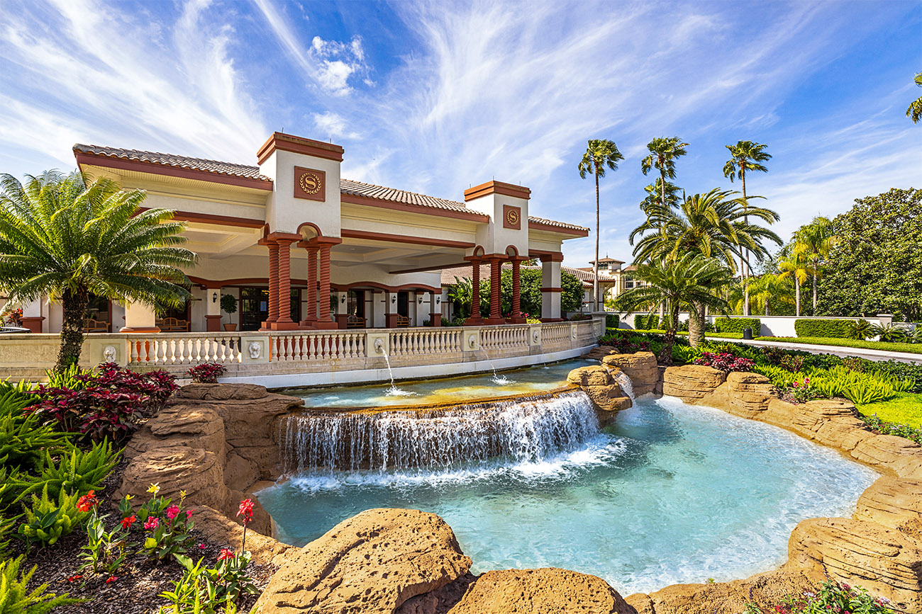 A waterfall fountain fills a rocky pool in front of a resort building.