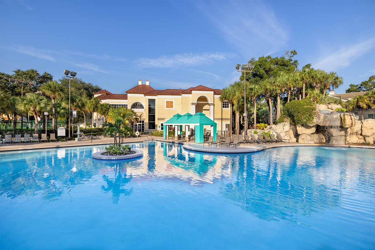 A clear pool reflects the Sheraton Vistana Resort under blue skies.