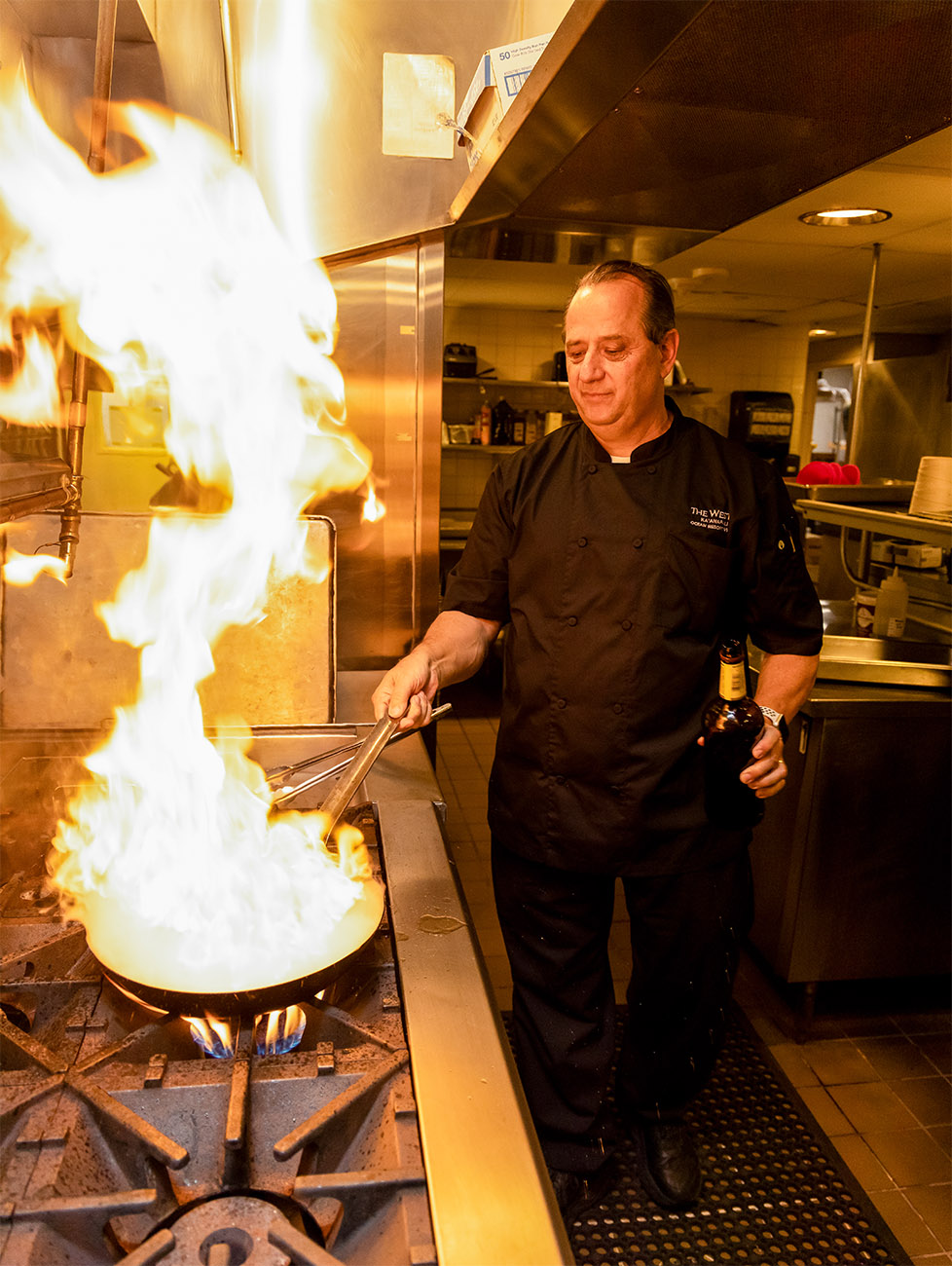 Fire erupts from the skillet as the chef adds tasty ingredients