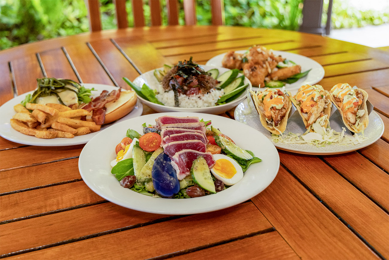 Four plates full of food sit on a wooden table