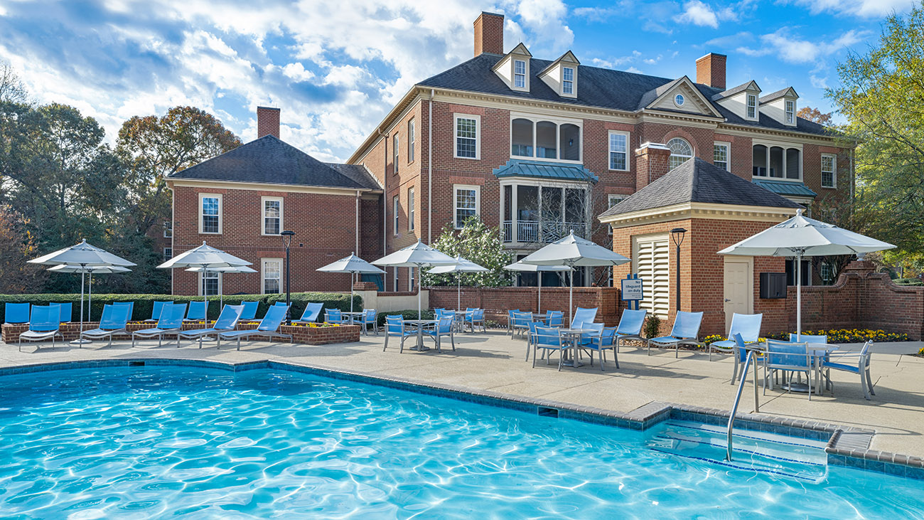 A serene resort pool with lounge chairs and green views in the background.