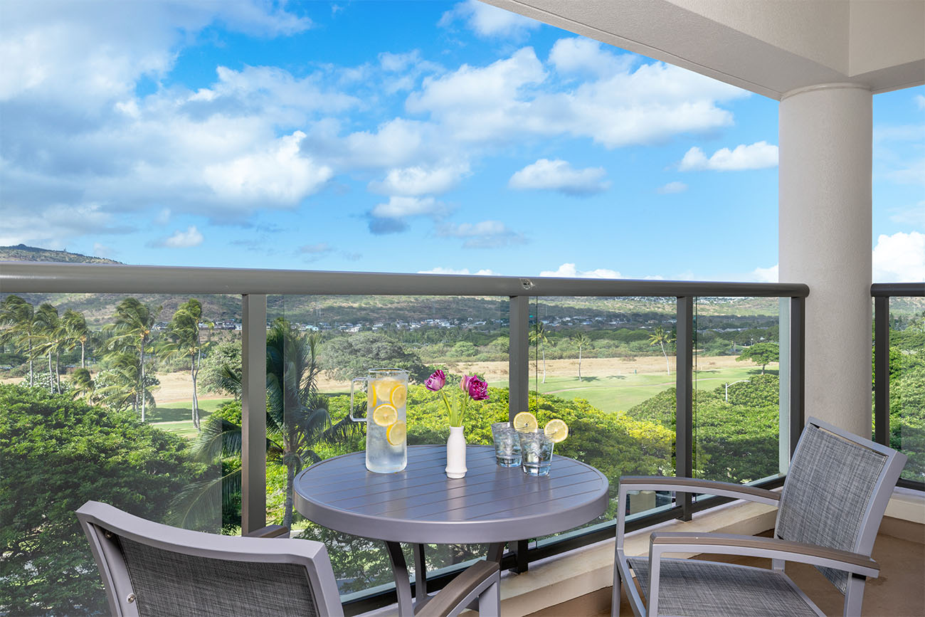 Two chairs and a table sit on a patio overlooking the scenic island horizon.