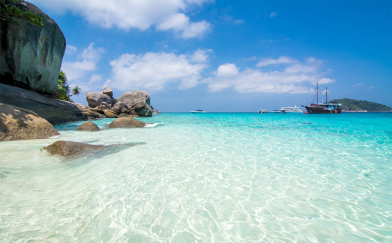Crystal-clear ocean water shows the sand below on the edge of a beach.