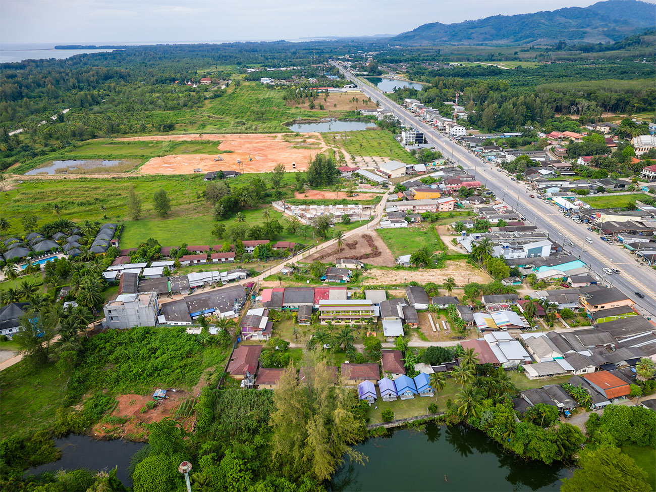 An aerial view of two Thai villages showcases natural settings and twisting roads.