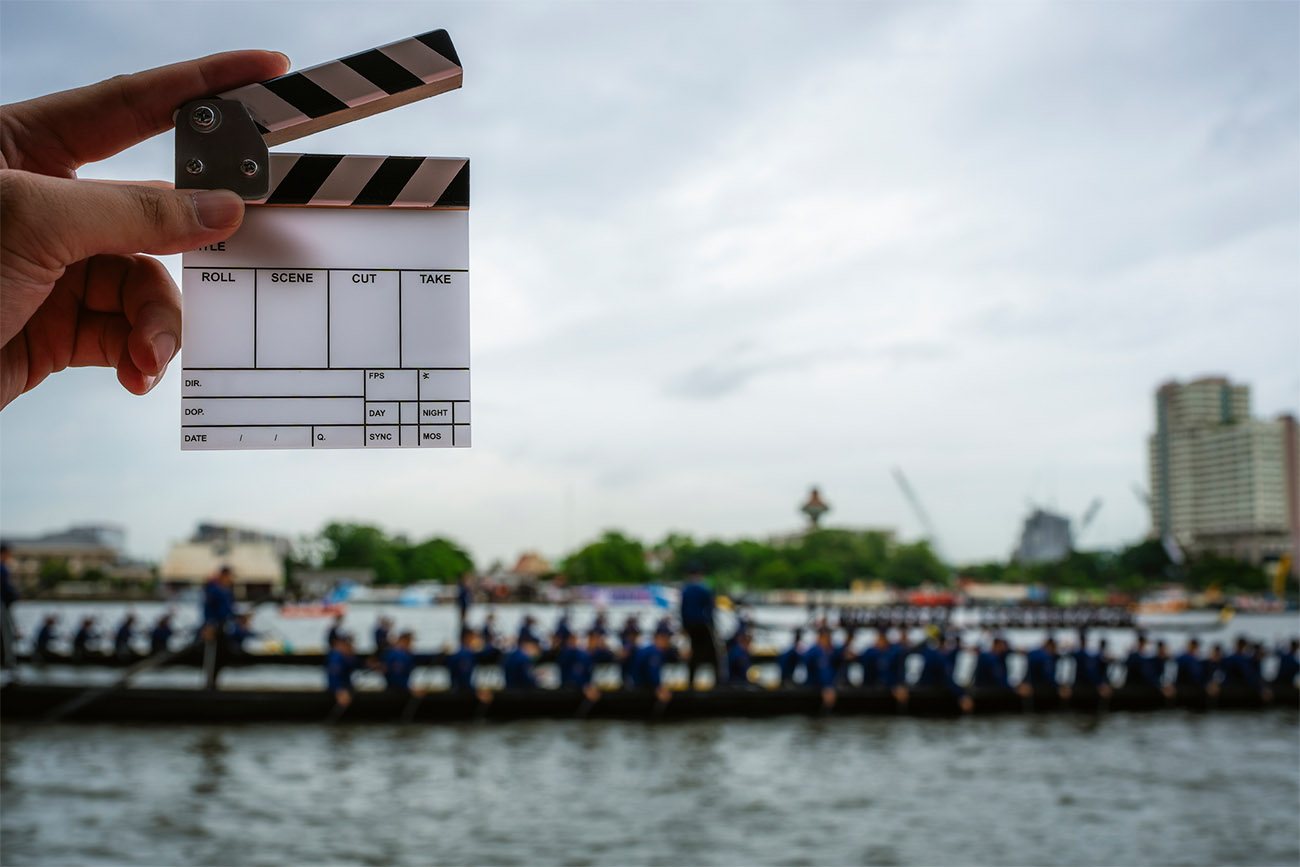 A clapper board is in focus as a city sits in the background.