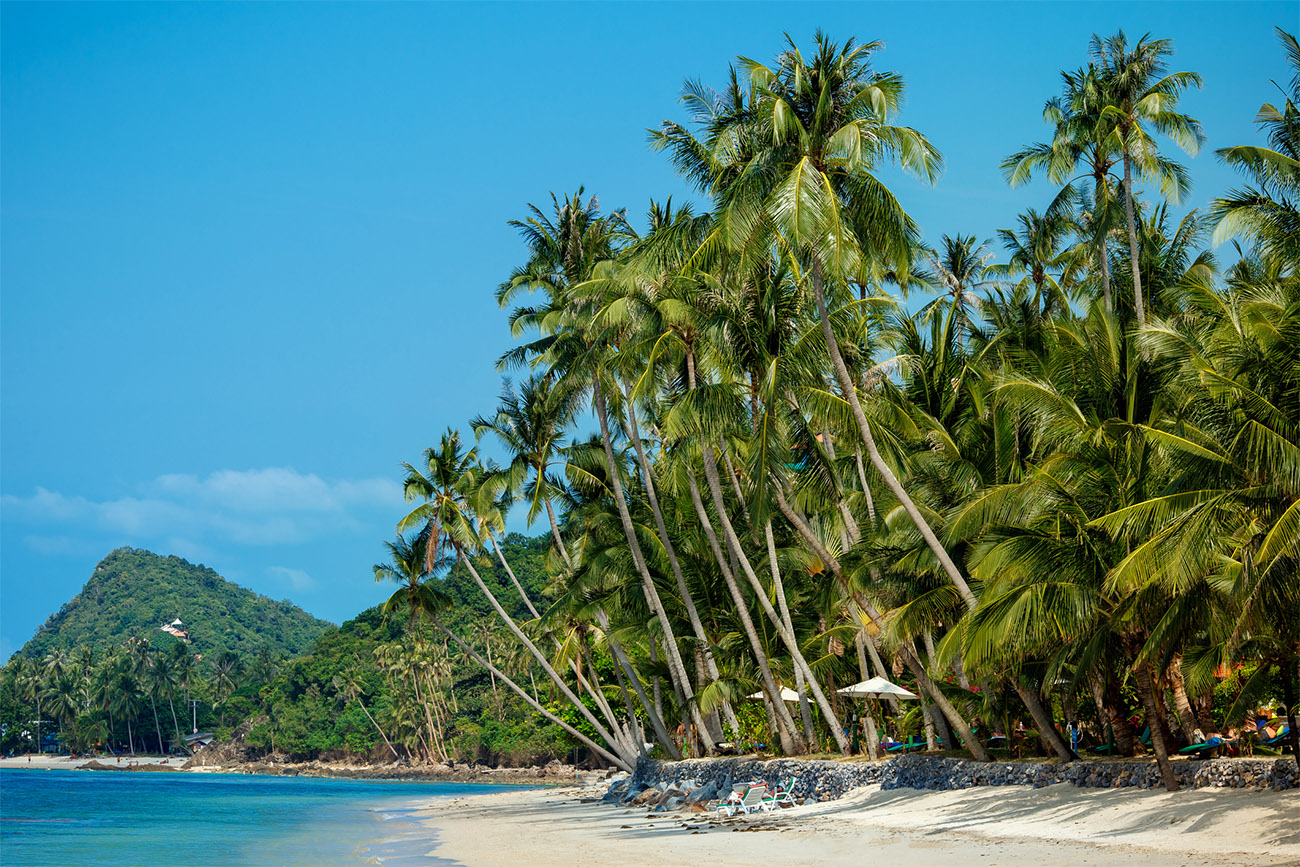 Two mini mountains sit in the middle of the water on a beach in Thailand.