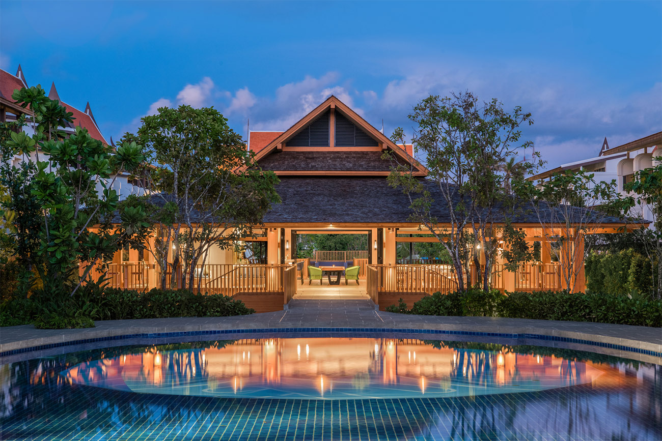 A restaurant and bar sit on the edge of a calm pool waiting for guests.