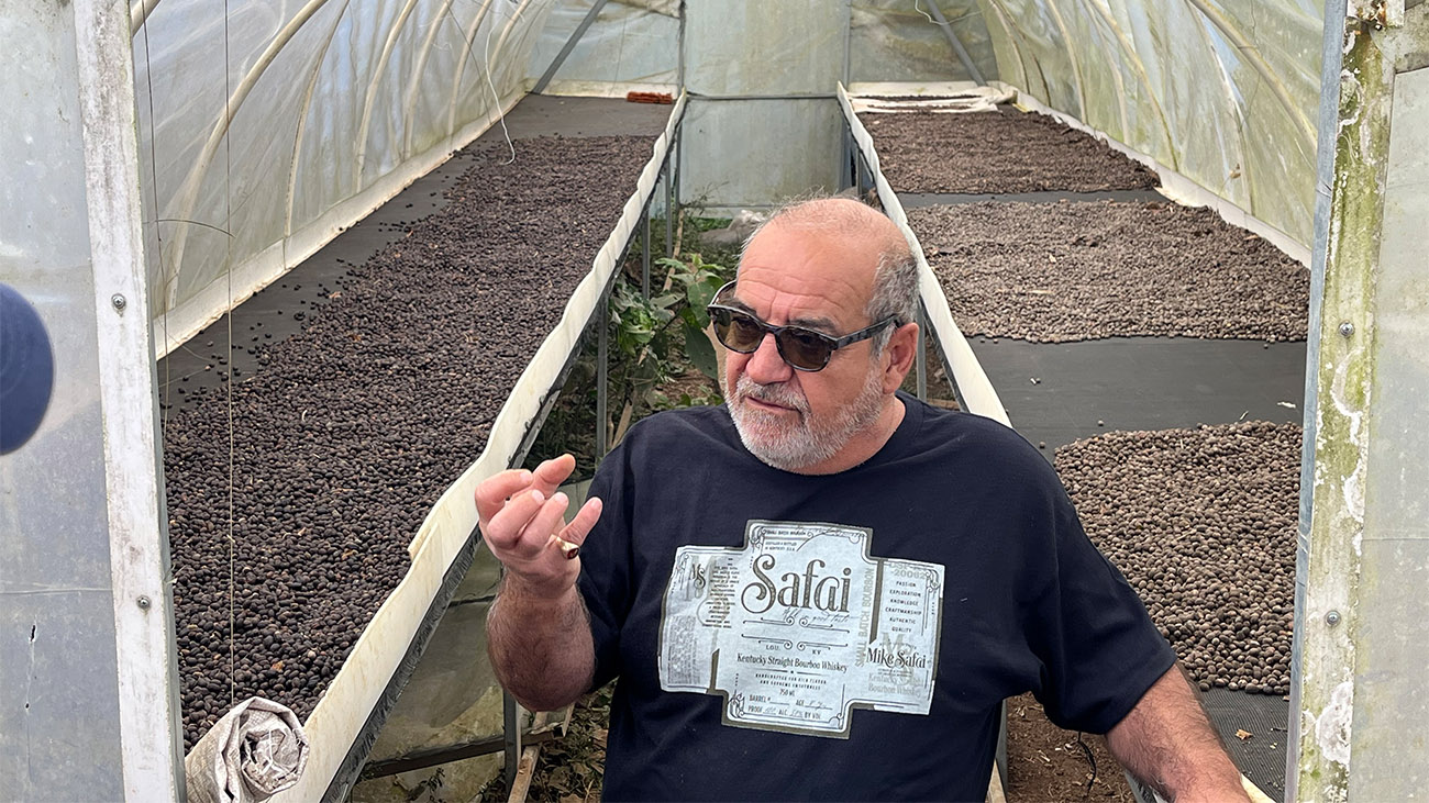 The found of the coffee company walks though a greenhouse where coffee is grown