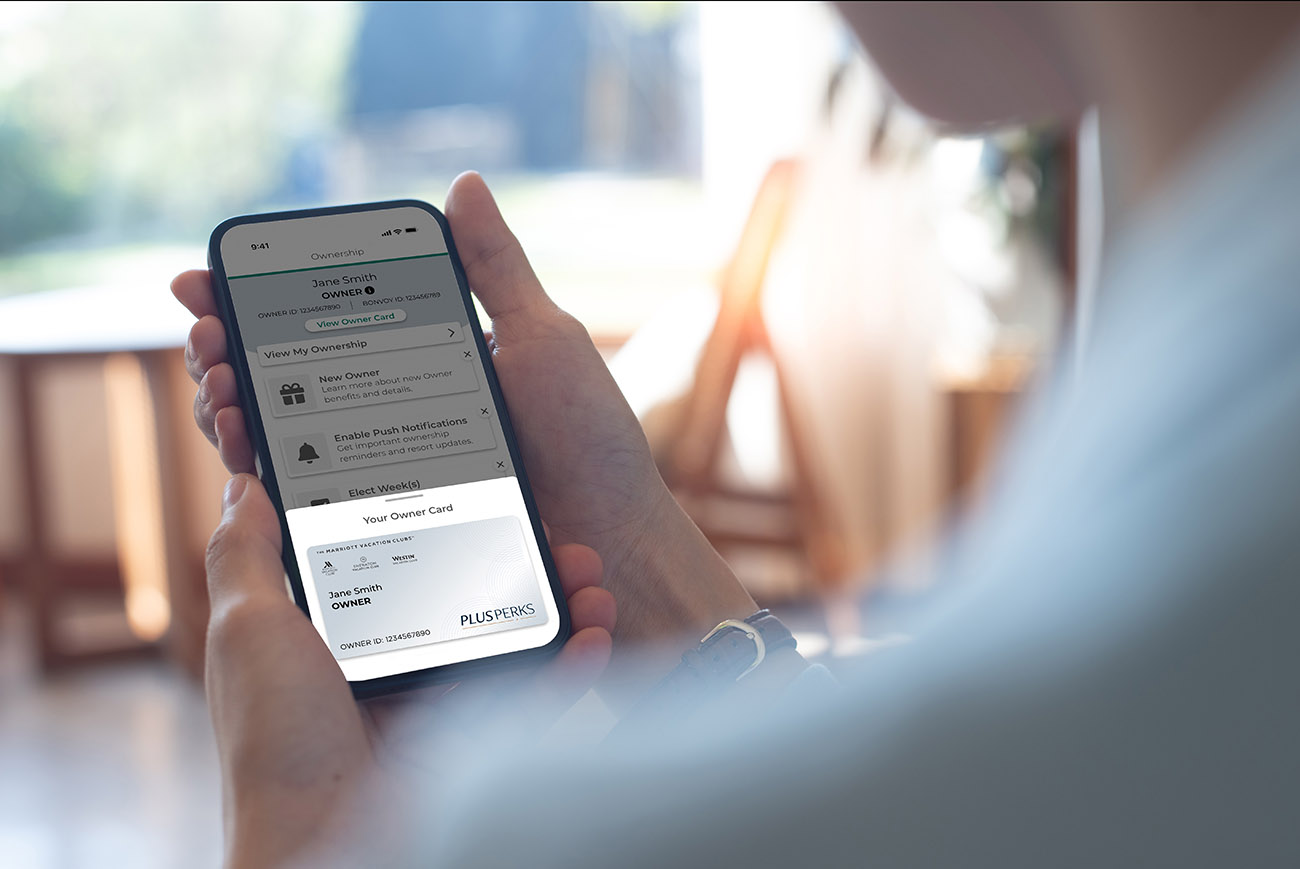 Woman looking at a phone with PlusPerks card information