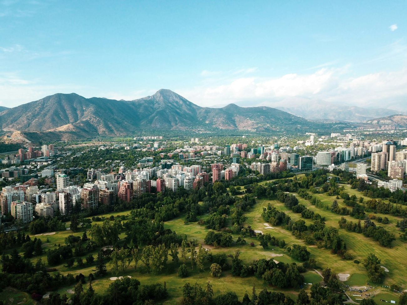 Aerial view of Santiago, Chile, with city buildings and mountains in the background.