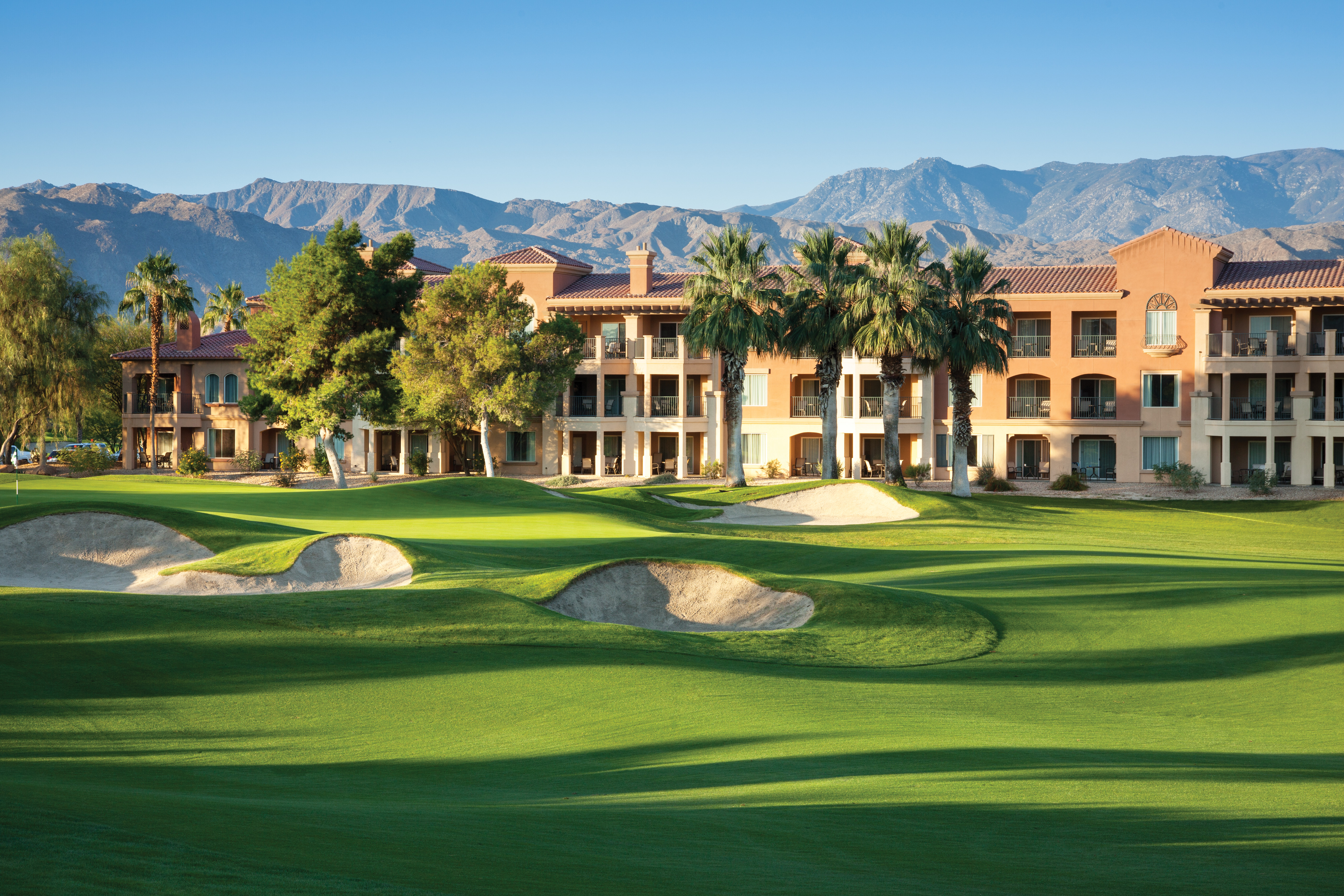 The wide fairway of Shadow Ridge Golf Club is surrounded by trees in front of a distant mountain.