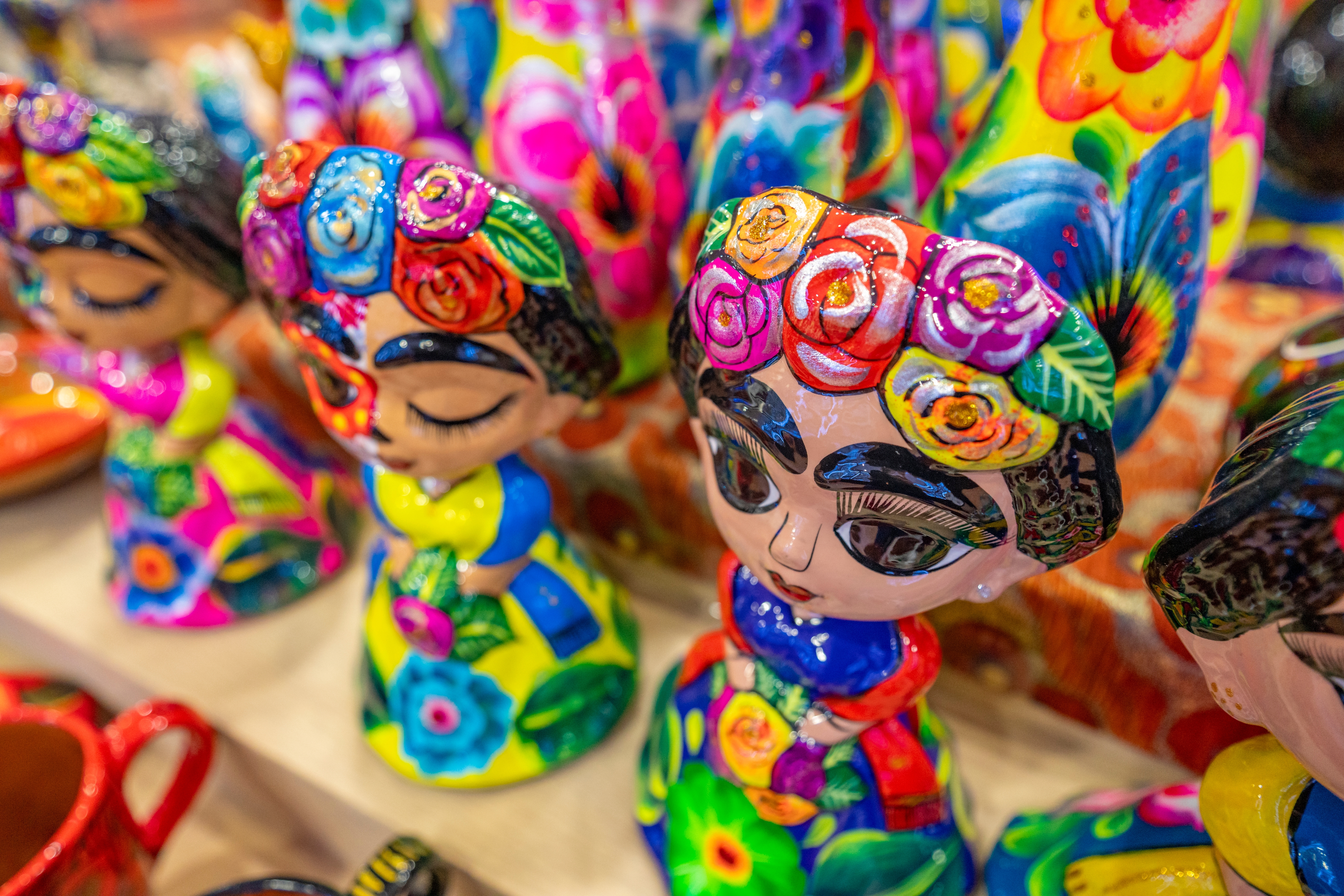 Bright and colorful Mexican figurines sit on a tabletop ready to be sold.