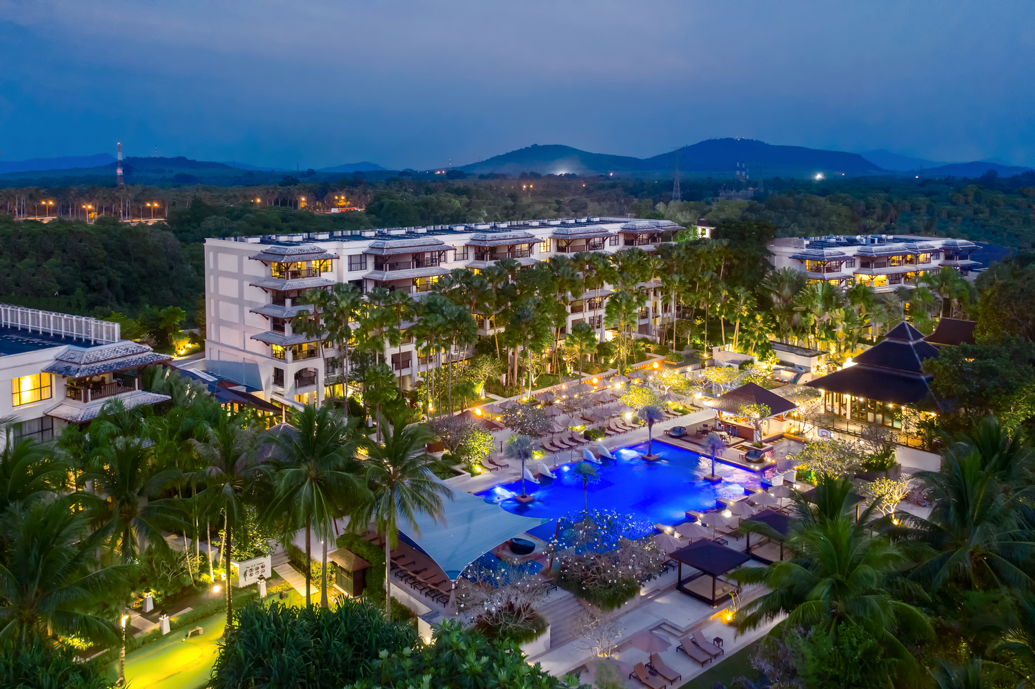Marriott’s Mai Khao Resort – Phuket at dusk featuring a large, illuminated pool.