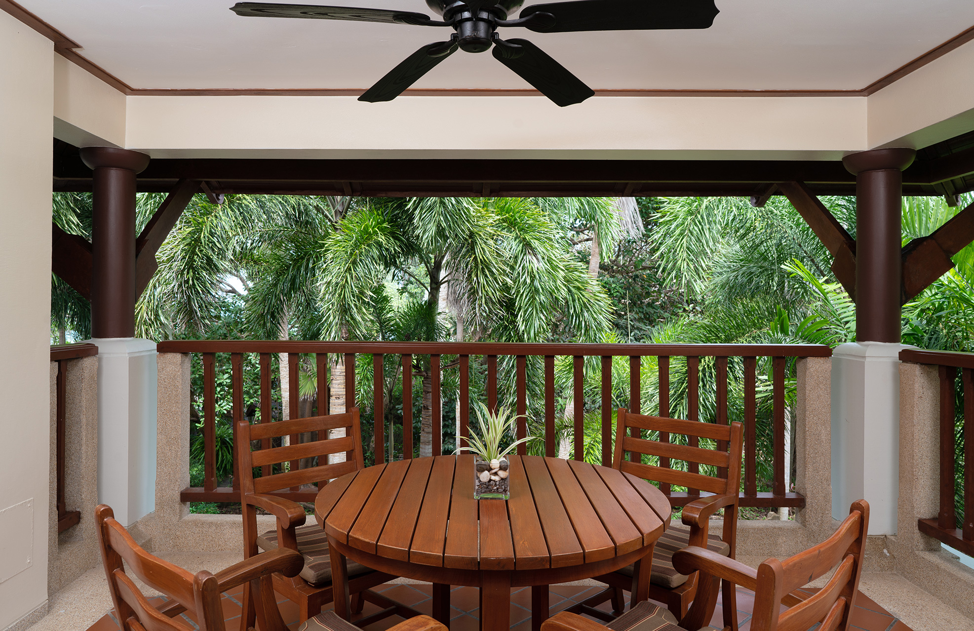 Wood deck with a round table surrounded by a backdrop of Palm Trees